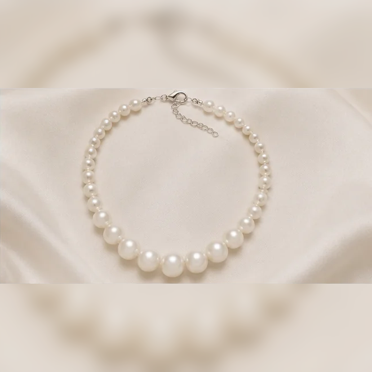 White pearl necklace on satin background