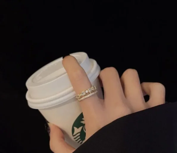 Elegant diamond ring worn while holding a takeaway coffee cup
