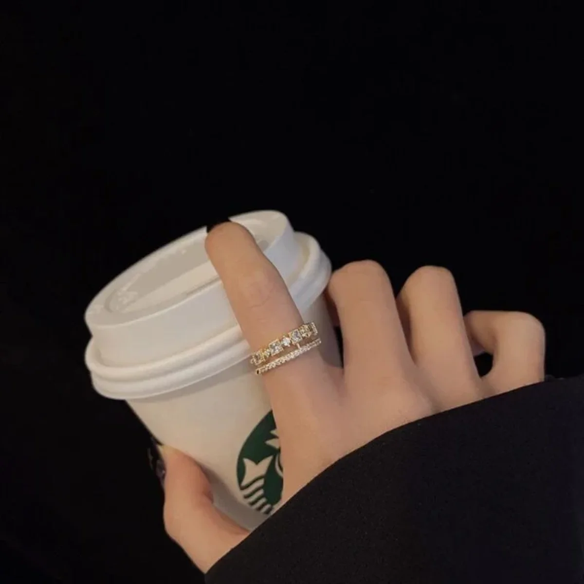 Elegant diamond ring worn while holding a takeaway coffee cup
