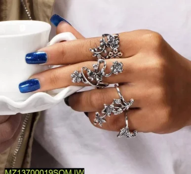 Ornate silver floral rings worn on a hand with blue nail polish