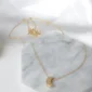 Gold necklace with a delicate crescent moon pendant on a marble surface