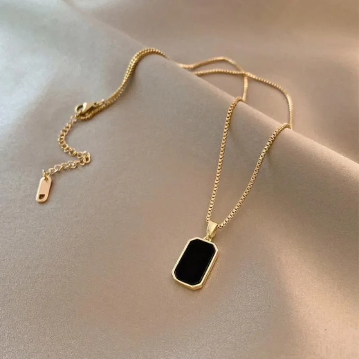 Gold chain necklace with black rectangular pendant