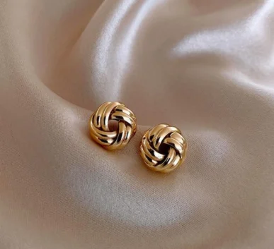 Elegant gold knot earrings on soft beige fabric