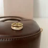 Elegant gold open ring displayed on a brown leather surface