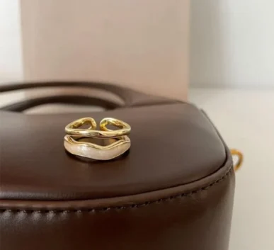 Elegant gold open ring displayed on a brown leather surface