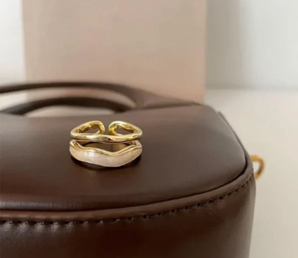 Elegant gold open ring displayed on a brown leather surface