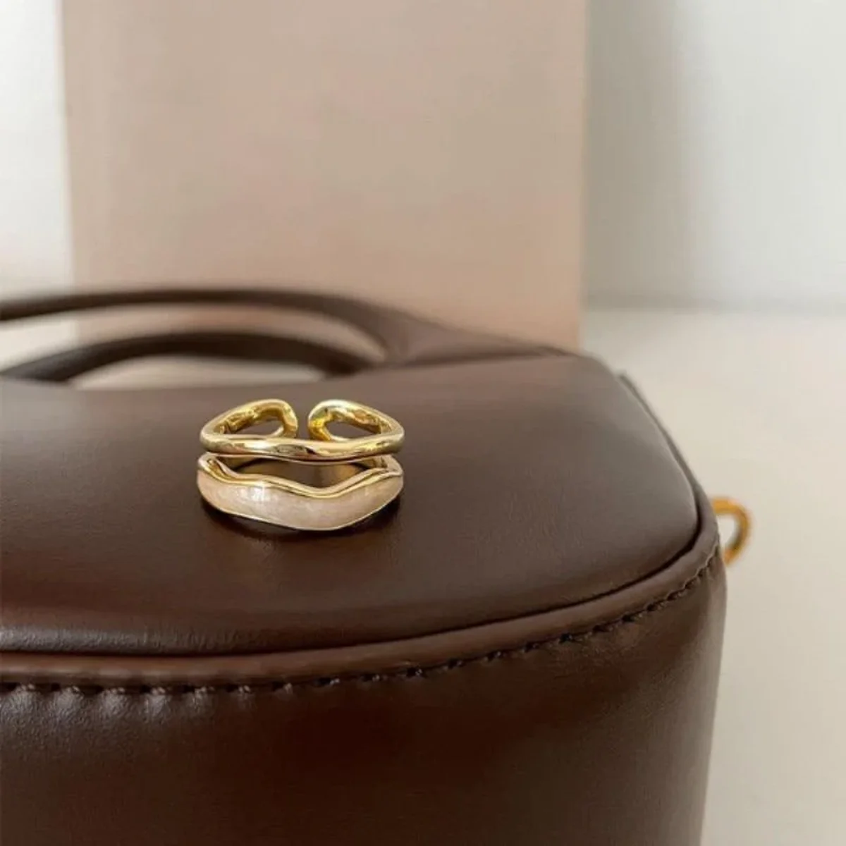 Elegant gold open ring displayed on a brown leather surface