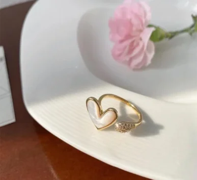 Elegant gold heart-shaped ring displayed on a white plate