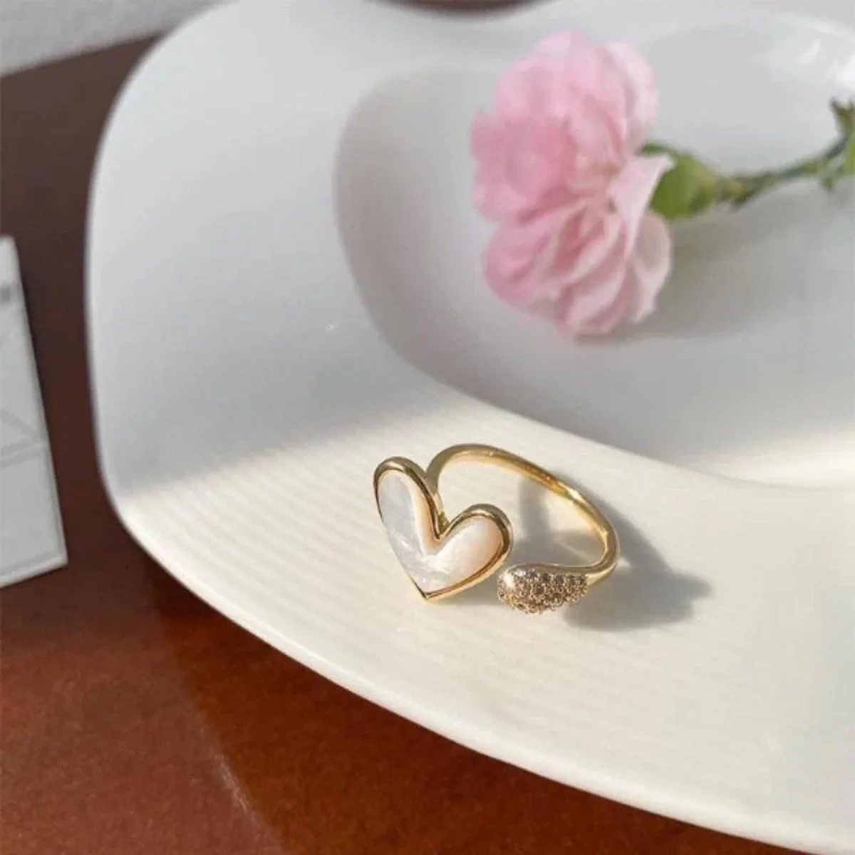 Elegant gold heart-shaped ring displayed on a white plate