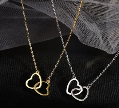 Gold and silver heart-shaped necklaces displayed on black fabric