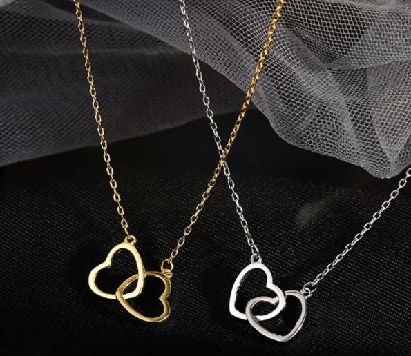 Gold and silver heart-shaped necklaces displayed on black fabric