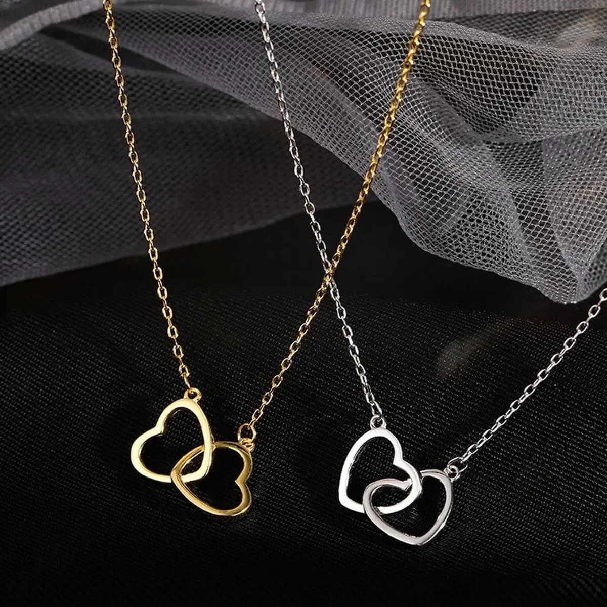 Gold and silver heart-shaped necklaces displayed on black fabric