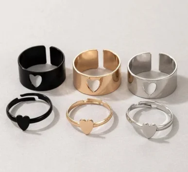 Collection of black, gold, and silver heart rings on a light background