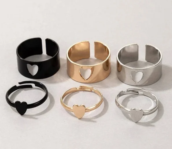 Collection of black, gold, and silver heart rings on a light background
