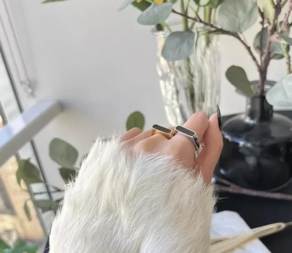 Modern statement rings worn on a hand with a soft white sleeve