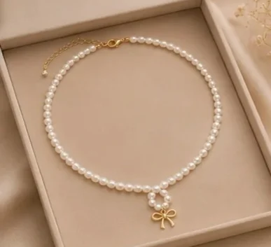 Elegant white pearl necklace with gold bow pendant