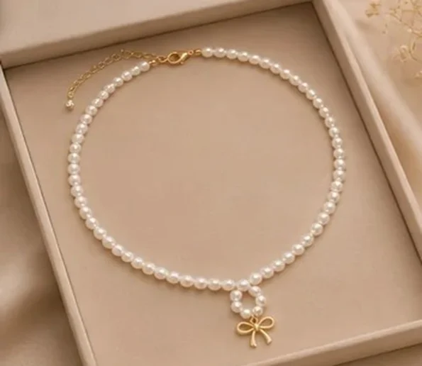 Elegant white pearl necklace with gold bow pendant
