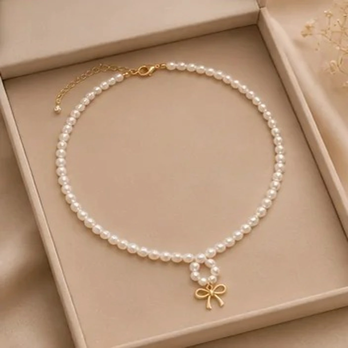 Elegant white pearl necklace with gold bow pendant