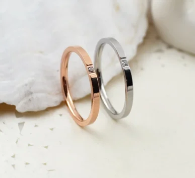 Rose gold and silver rings with small diamond accents on a white surface