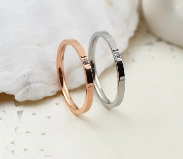 Rose gold and silver rings with small diamond accents on a white surface