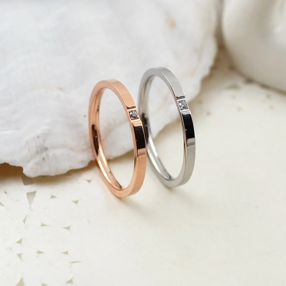Rose gold and silver rings with small diamond accents on a white surface
