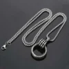 Silver chain necklace with a round pendant on a dark background