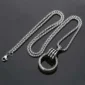 Silver chain necklace with a round pendant on a dark background