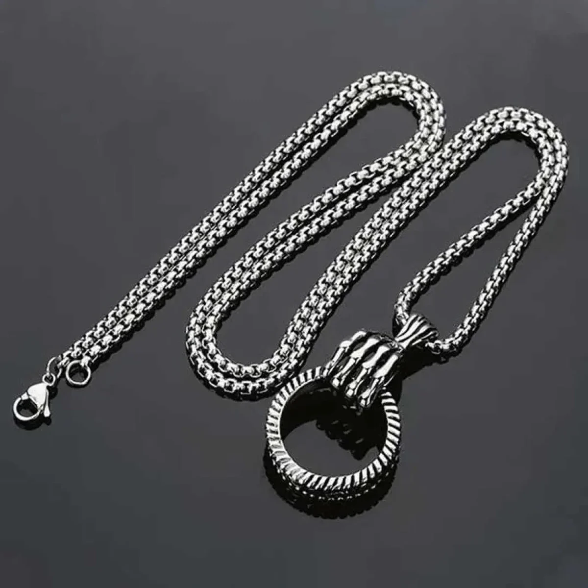Silver chain necklace with a round pendant on a dark background