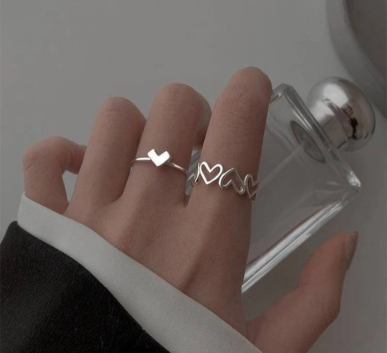 Silver heart and love-themed rings worn on a hand