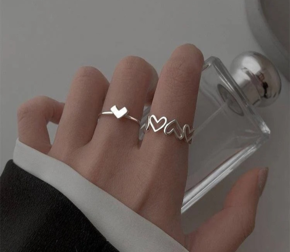 Silver heart and love-themed rings worn on a hand