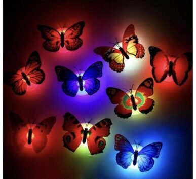 Colorful decorative butterflies illuminated by red, blue, green, yellow, and purple lights on a dark background