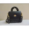 Black handbag with gold chain strap and bee-shaped decorative emblem