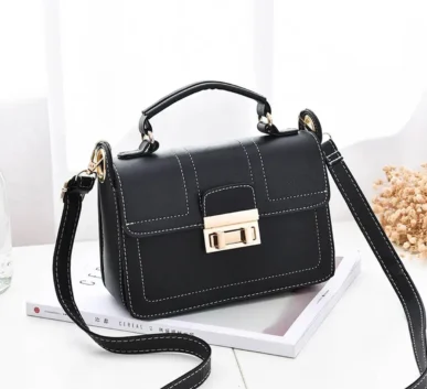Black women’s handbag with white stitching and gold-tone clasp