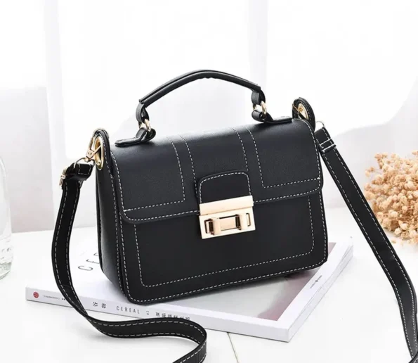 Black women’s handbag with white stitching and gold-tone clasp