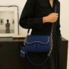 Elegant navy blue women’s shoulder bag with textured finish, curved flap, gold-tone trim, and chain strap.