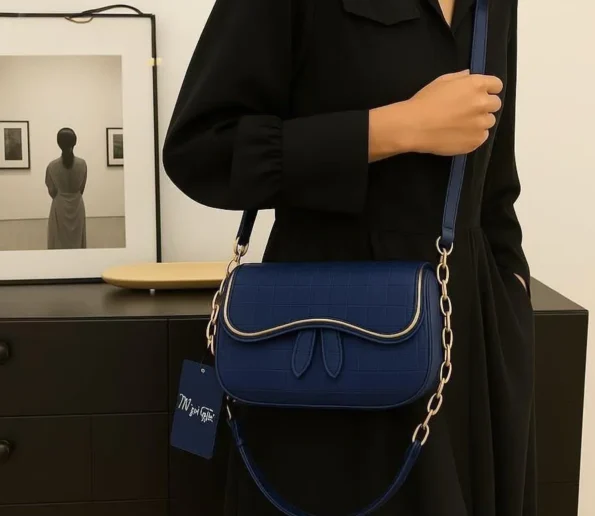 Elegant navy blue women’s shoulder bag with textured finish, curved flap, gold-tone trim, and chain strap.