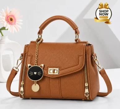 Brown women’s handbag with gold details and cat charm