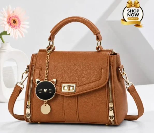 Brown women’s handbag with gold details and cat charm