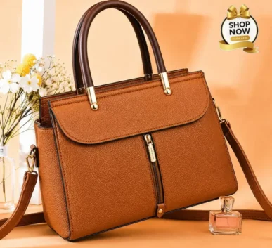 Elegant brown women’s handbag with top handles, front zipper, and shoulder strap.