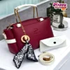 Burgundy women’s handbag with white handles and decorative charm