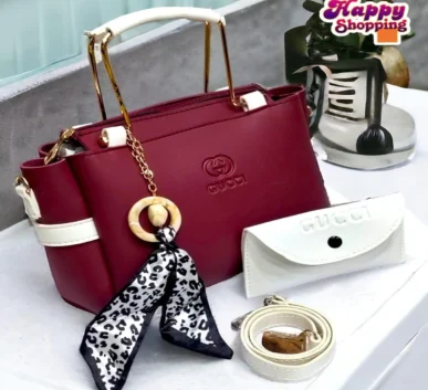 Burgundy women’s handbag with white handles and decorative charm