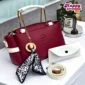 Burgundy women’s handbag with white handles and decorative charm