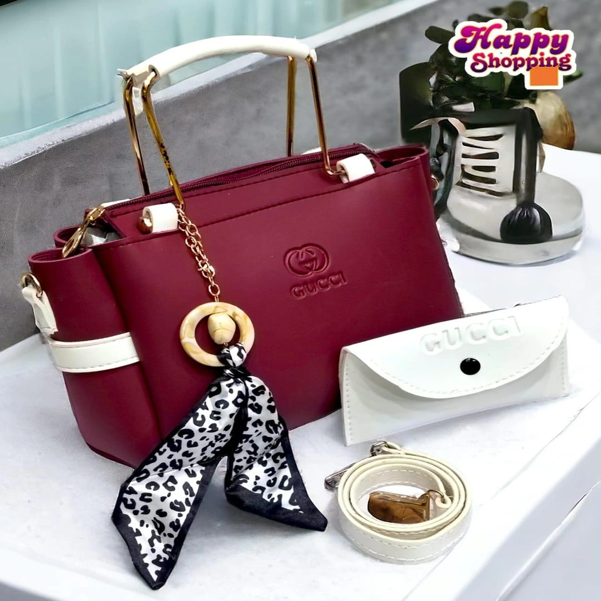 Burgundy women’s handbag with white handles and decorative charm