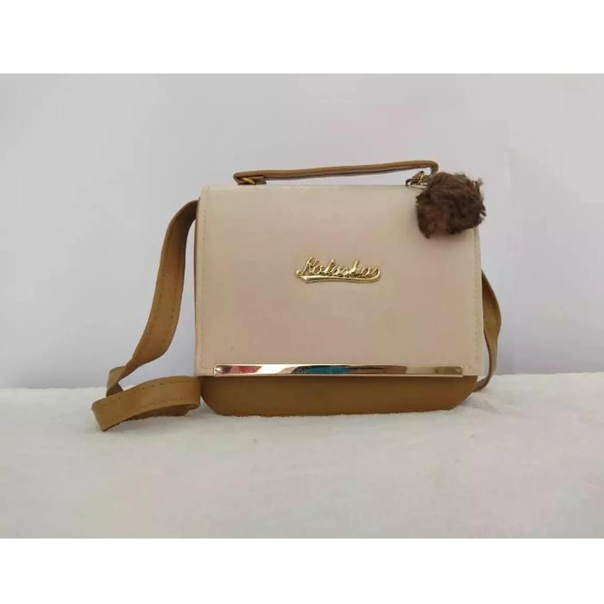 Cream and brown crossbody handbag with top handle and decorative pom pom