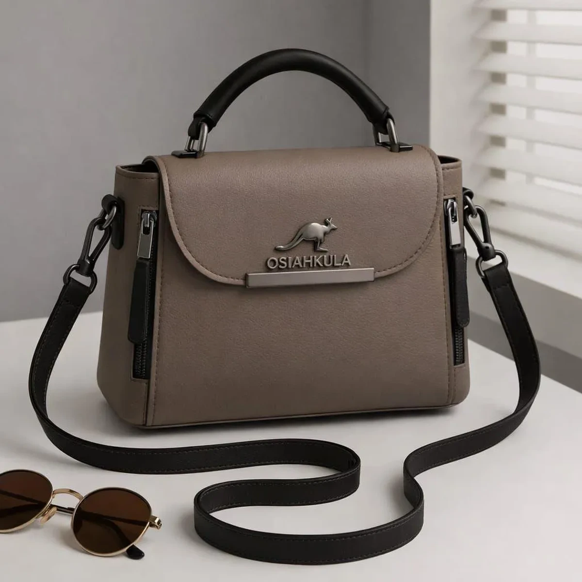 Taupe women’s handbag with black top handle and adjustable shoulder strap