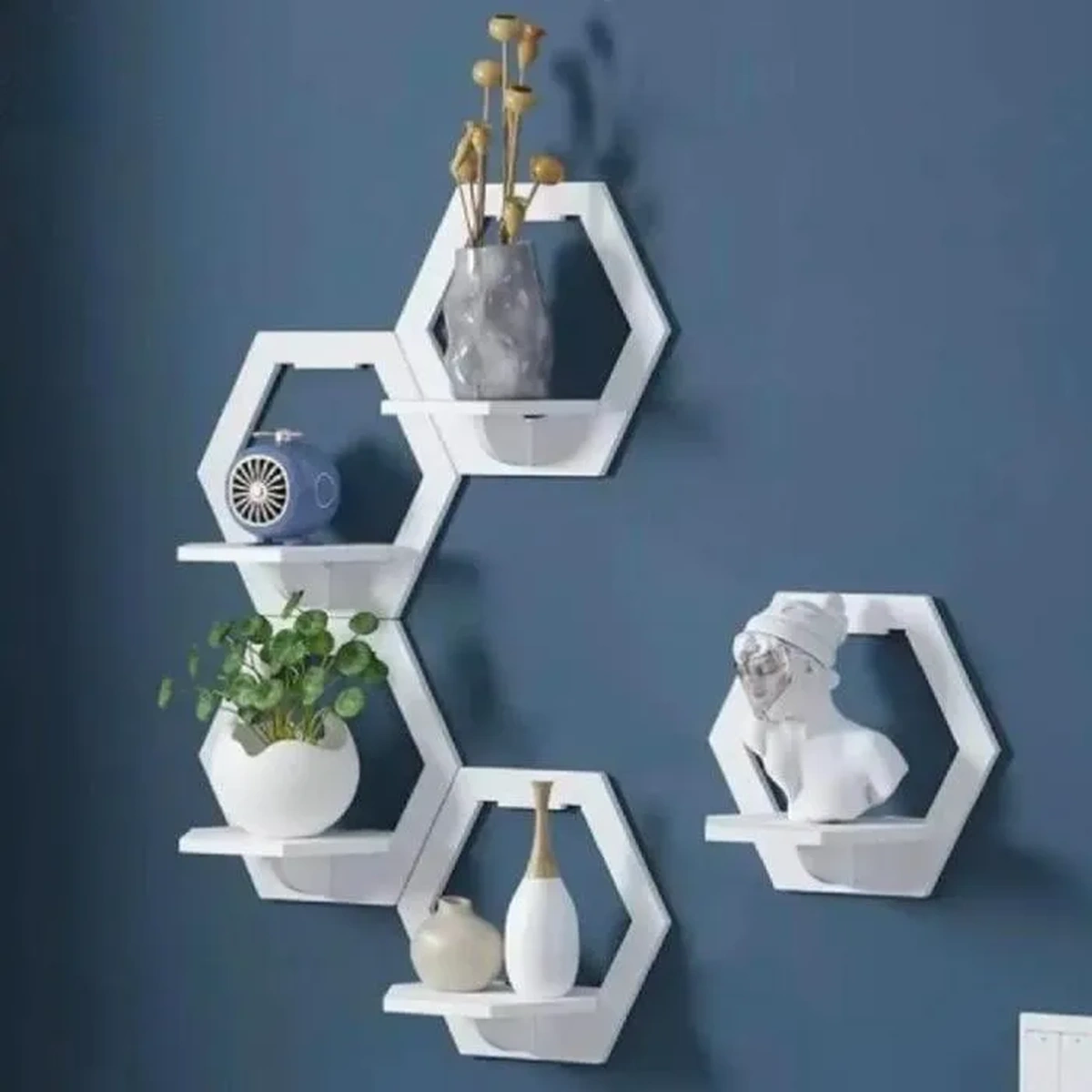 Modern white hexagon wall shelves with decorative vases, plant, fan, and sculpture