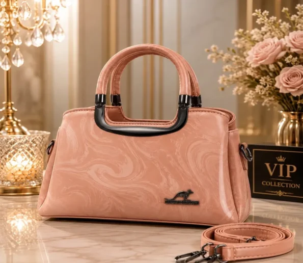 Elegant pink women’s handbag with dual handles, textured finish, and adjustable shoulder strap.