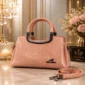 Elegant pink women’s handbag with dual handles, textured finish, and adjustable shoulder strap.
