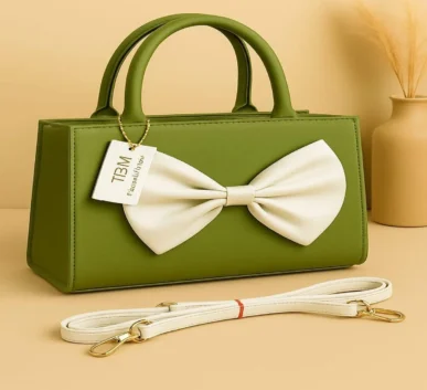 Green handbag with white bow and shoulder strap