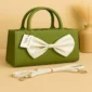 Green handbag with white bow and shoulder strap